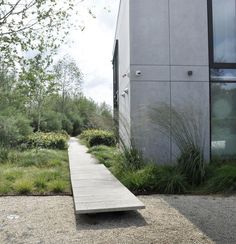 a concrete bench sitting in front of a building next to a grass covered field and trees