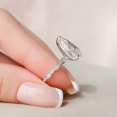 a woman's hand with a diamond ring on top of her finger and white nail polish