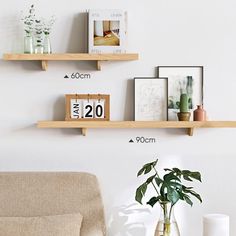 two wooden shelves on the wall above a couch with a vase and plant in it