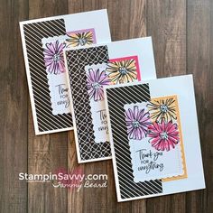 three cards with flowers on them sitting next to each other in front of a wooden background