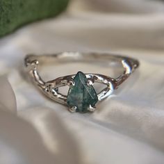 a close up of a ring with a stone in the middle on a white cloth