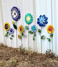 several colorful flowers are placed next to a white fence