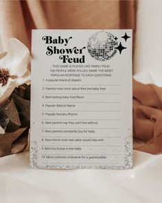 a baby shower checklist is sitting on a bed with flowers and blankets in the background