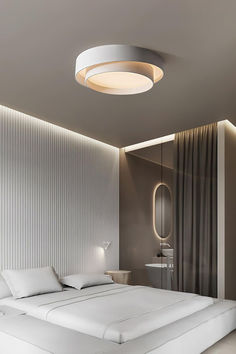 a large bed sitting under a round light in a bedroom