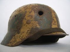 an old helmet with holes on the side and a visor is sitting up against a white background