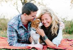 a couple cuddles with their dog on a blanket