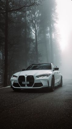 a white sports car parked on the side of a road in front of some trees