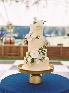 a three tiered cake with white flowers and greenery