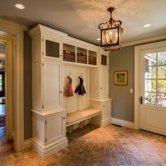 an entryway with built in bench and coat rack next to the door, lights on