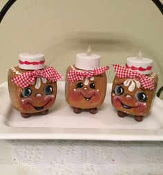 three little jars with faces painted on them sitting on a white tray next to each other