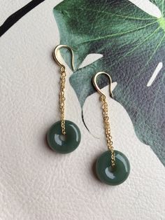 A gorgeous pair of dark green jade donut earrings. The royal style long dangles gold earrings, paired with the vintage green jade circles are eye-catching and elegant. Hade made with high-quality materials only and comes in the gift-worthy package, perfect as a gift for yourself or your loved ones. Some highlights of this pair of breath-taking natural green jade drop earrings are: *High-quality guaranteed Hand made with grade-A natural dark green jade. The chain is gold plated, ensure long lasti Nickel-free Round Jade Earrings, Vintage Jade Round Earrings, Jade Dangle Earrings For Pierced Ears, Pierced Jade Dangle Earrings, Elegant Green Circular Earrings, Dark Green Round Jade Jewelry, Handmade Dark Green Round Jewelry, Jade Earrings Drop, Earrings Gold Long