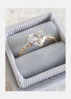 an engagement ring in a box on a white cloth covered surface with the words, i do not know what this is