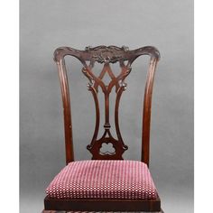 an antique wooden chair with pink fabric seat pad