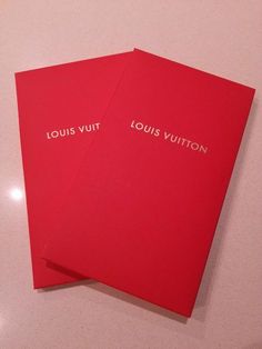 two red louis vuitton books sitting on top of a white table next to each other