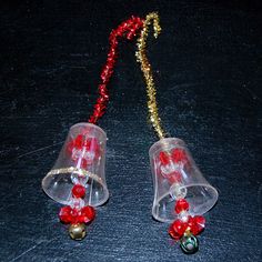 two plastic bells with red beads on a black surface next to a gold beaded chain