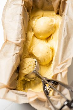 two scoops of ice cream in a paper bag with tongs next to it