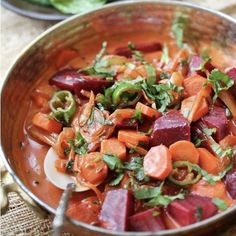 a metal bowl filled with carrots and other veggies on top of a table