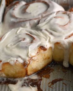 a cinnamon roll with icing sitting on top of a pan