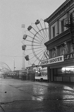 an old black and white photo of a street with a ferris wheel in the background