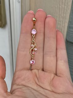 a person is holding a pink and gold colored necklace in their left hand, while the other hand holds it