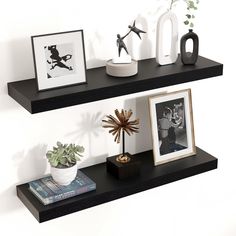 two black shelves with pictures and other items on them, one shelf is holding an art piece