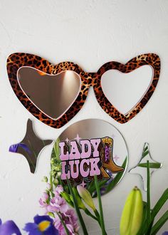 two heart shaped mirrors with the word lady luck on them next to flowers and purple orchids