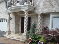 a brick house with white columns and flowers