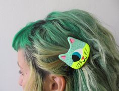 a woman with green hair has a cat brooch on it's back end