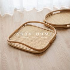 two woven trays sitting on top of a wooden floor in front of a window