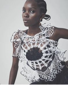 a woman wearing a white top with black lace on it's shoulders and neck