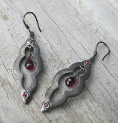 A unique bohemian pair of Moroccan-inspired dangle earrings handcrafted in oxidized sterling silver accented with a garnet and ruby. A stunning and one-of-a-kind earring that make a great birthstone earrings for the month of January(Garnet) and Ruby(July) (E.96) *Follow us @belesasjewelry on Instagram for promotions/giveaways *LIKE* us on Facebook http://www.facebook.com/Belesas  *If you like the ring, please click on the "Pin It" icon ---------------------------------------------------- ENTER M Black Earrings Dangle, Earrings Stone, Earrings Gemstone, Birthstone Earrings, Nail Jewelry, Dope Jewelry, Statement Earring, Garnet Earrings, Funky Jewelry