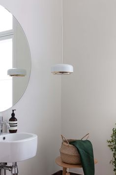 a white bathroom with a round mirror and wooden stool