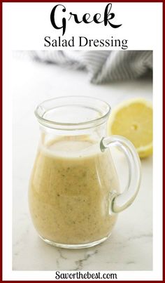 a glass pitcher filled with salad dressing next to a lemon slice