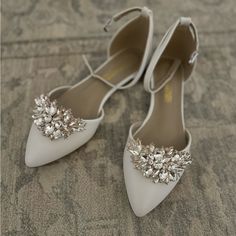 a pair of white shoes with jeweled buckles