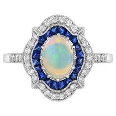 an opalite and diamond ring with blue sapphires in the center, surrounded by white diamonds