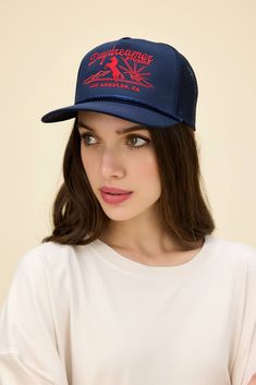 a woman wearing a blue hat with red lettering on the front and side, she is looking at the camera