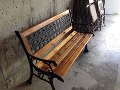 a wooden bench sitting next to a wall with metal designs on it's back