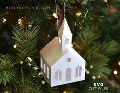 a white paper church ornament hanging from a christmas tree