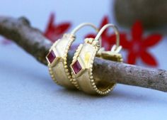 Wide ornamented solid yellow, white or rose gold hoop earrings with rubies in 14k, 18, or 22k gold. These Gold Hoop earrings are a special take on ornamental jewelry.These wide oriental-style hoops feature beaded edges and are set with beautiful square shiny red rubies.Rubies, the birthstone of July, are considered the king of gems and represent love, health, and wisdom. It was believed wearing a fine red Ruby bestowed good fortune on its owner. It is a favorite gem among those in power and thos Elegant Small Hoop Earrings With Bezel Setting, Fine Jewelry Bezel Set Hoop Earrings As Gift, Anniversary Hoop Earrings With Bezel Setting, Gold Hoop Earrings With Bezel Setting, Bezel Set Hoop Huggie Earrings As Gift, Hoop Huggie Earrings With Bezel Setting As Gift, Gift Huggie Hoop Earrings With Bezel Setting, Ornamental Jewelry, Ruby Gold Earrings