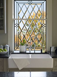 a white sink sitting under a window next to a counter top with fruit on it