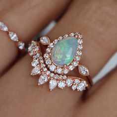 an opal and diamond ring is shown on someone's hand with her wedding band