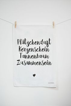 a tea towel hanging on a clothes line with words written in different languages and symbols