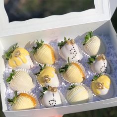 a box filled with lots of white and yellow chocolate covered strawberries next to each other