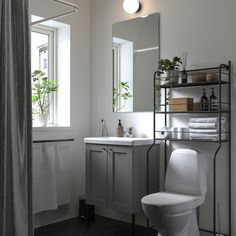 a white toilet sitting next to a bathroom sink under a mirror and a shelf filled with towels