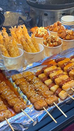 many different types of food on sticks in front of some bowls with sauces and other condiments