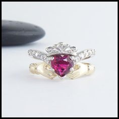 Two piece ring set in 14K White and Yellow Gold. One ring is set with a 1ct heart shaped Ruby and has 5 diamonds on either side. The other ring interlocks and holds the heart creating the traditional Claddagh. Diamond Heart Cut Ring Hallmarked, 14k Gold Heart Cut Jewelry With Center Stone, Heart Cut Diamond Ruby Ring For Promise, Heirloom Heart Cut Gemstone Ring, 14k Gold Heart-shaped Jewelry With Center Stone, Hallmarked Heart Cut Promise Ring, Heart Cut Ring With Center Stone In 14k Gold, Heirloom Heart Cut Ring With Prong Setting, Heirloom White Gold Heart Cut Ring