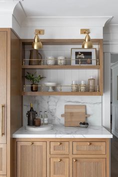 a kitchen with wooden cabinets and marble counter tops, gold accents on the upper shelves