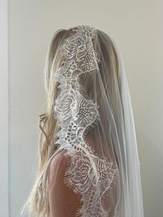 the back of a bride's veil with white lace on it and an intricate design