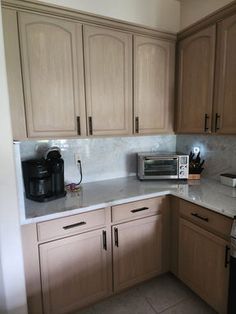 a kitchen with brown cabinets and white counter tops is seen in this image from the doorway