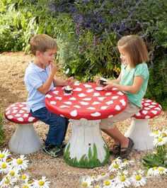 two children sitting at a mushroom shaped table with flowers in the backgroung